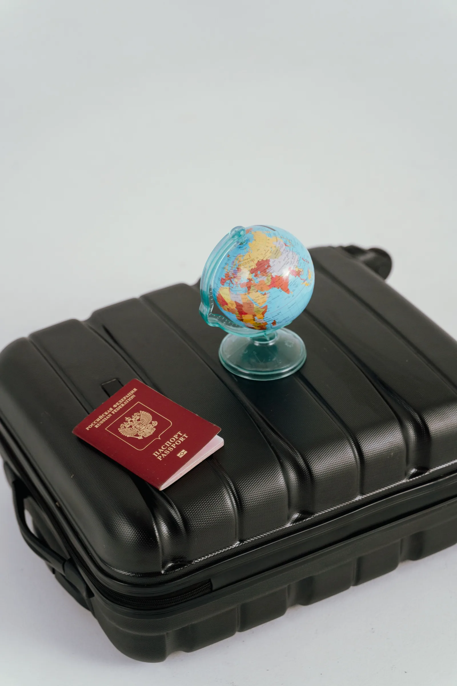 A closed foreign passport and small globe on a suitcase; generic travel illustration, not a Malaysian passport or MM2H pass.